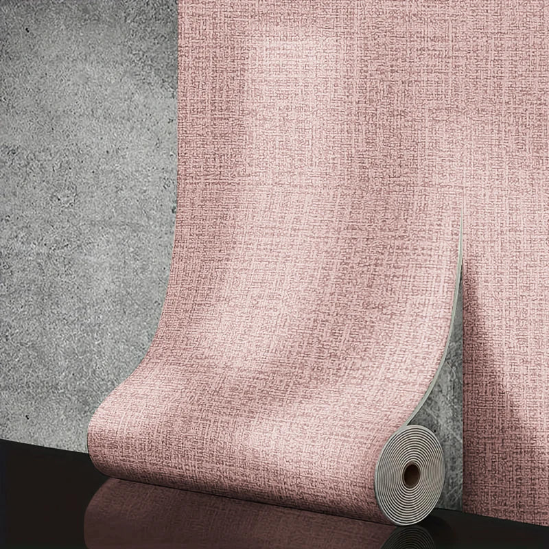 Roll of pink textured wallpaper against a gray concrete wall.