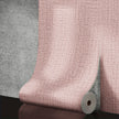 Roll of pink textured wallpaper against a gray concrete wall.