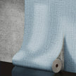 Roll of blue textured wallpaper on a concrete surface