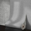 Roll of textured gray wallpaper on a concrete surface
