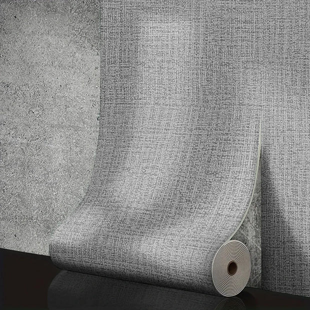 Roll of textured gray wallpaper on a concrete surface