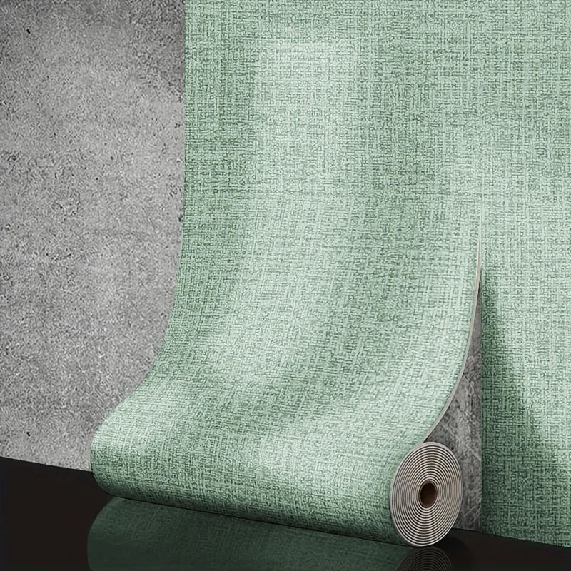 Roll of green textured wallpaper on a gray surface