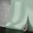 Roll of green textured wallpaper on a gray surface