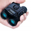 Black binoculars held in a hand with a clear background