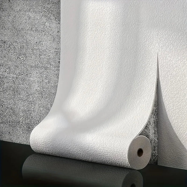 Roll of white textured wallpaper against a gray concrete wall.