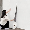 Person unrolling wallpaper in a room