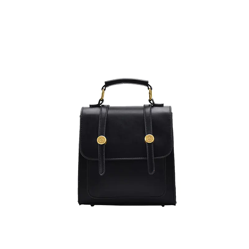 Black leather handbag with gold buttons on a white background