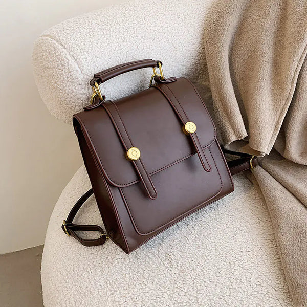 Brown leather backpack with gold accents on a textured surface