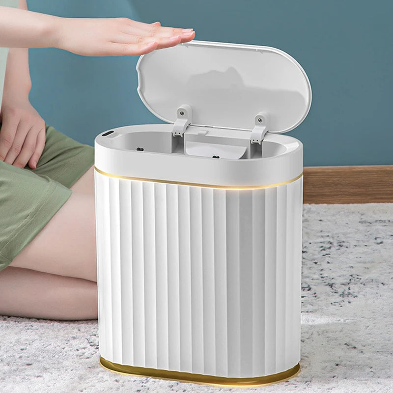 White trash bin with gold accents on a marble surface, person sitting nearby.