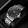 Silver wristwatch with black dial on a dark background