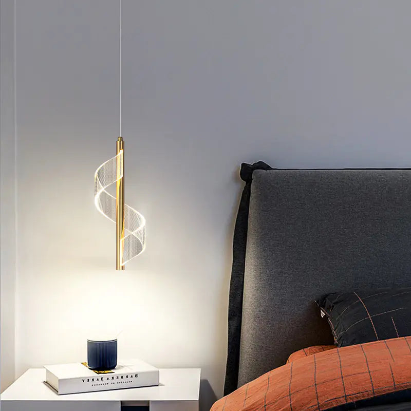 Modern pendant light hanging above a bed with a nightstand in a bedroom setting.