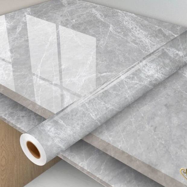 Roll of gray marble-patterned vinyl wrap on a surface