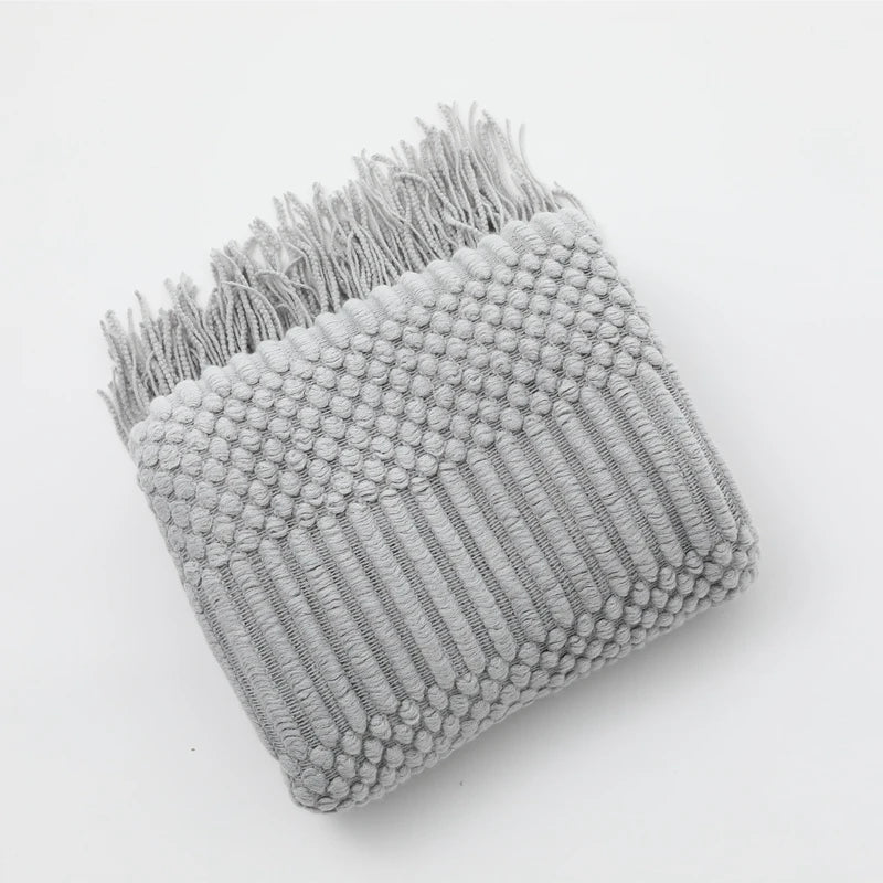 Gray textured throw blanket with fringe on a white background