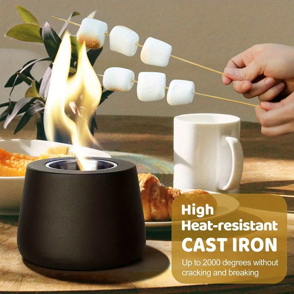 Person roasting marshmallows over a small fire pit on a table with food and a mug.