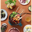 Assorted skewered dishes and ingredients on a textured surface