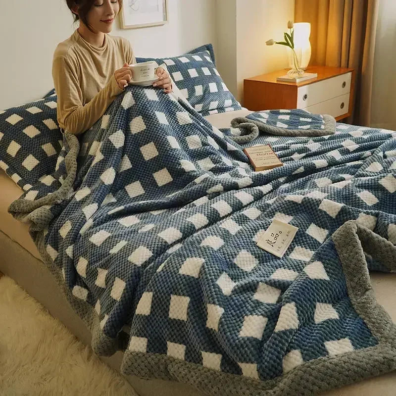 Person sitting on a bed with a blue and white checkered blanket, holding a cup.