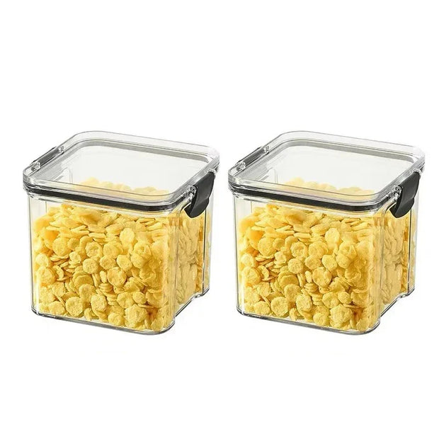 Two glass storage containers with lids filled with yellow cereal on a white background