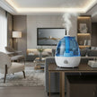 Blue and white air humidifier on a table with text describing its benefits.