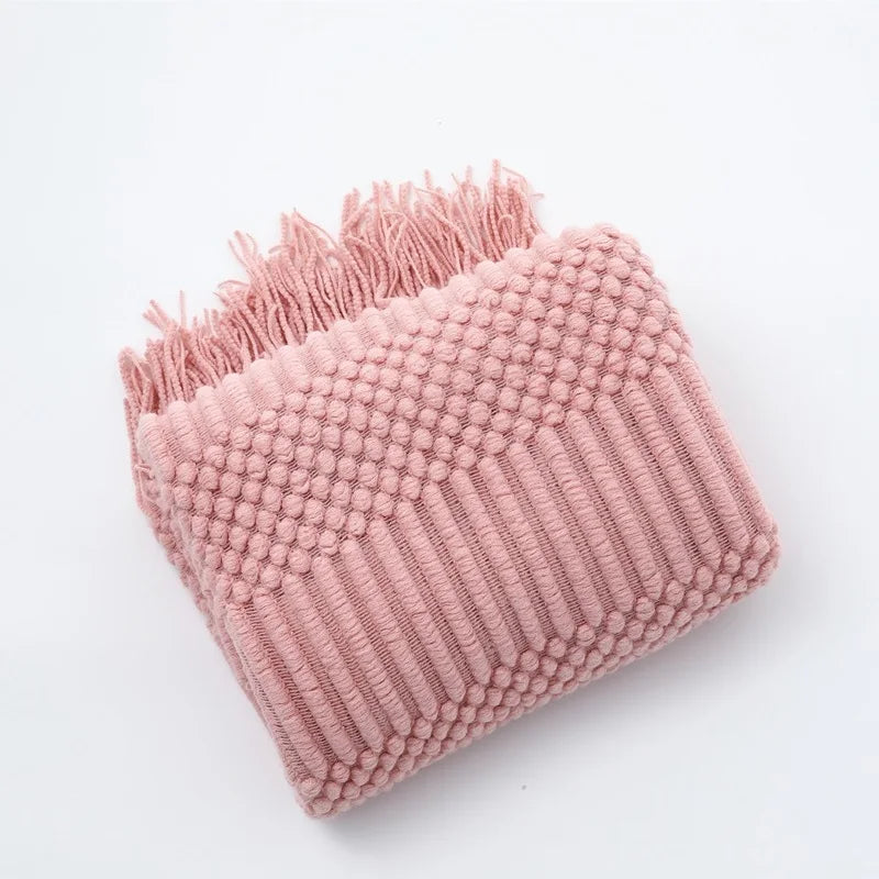 Pink textured blanket with fringe on a white background