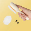 Hand holding a white brush with a yellow background