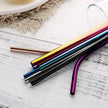 Set of colorful metal straws on a wooden surface