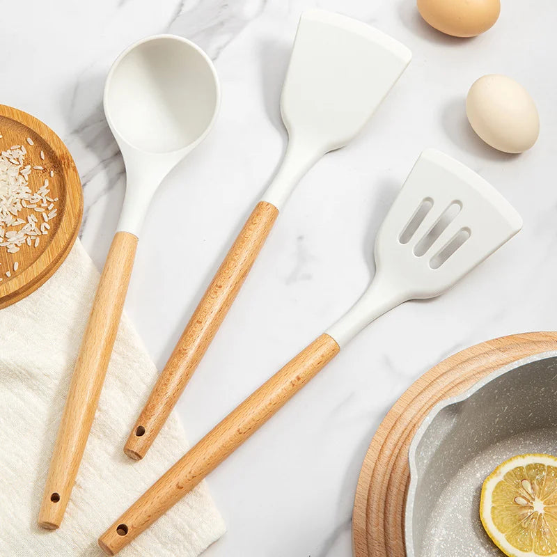 Set of kitchen utensils with wooden handles on a marble surface.
