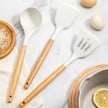 Set of kitchen utensils with wooden handles on a marble surface.