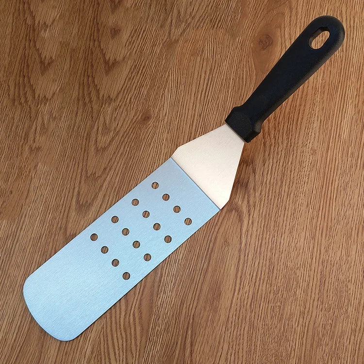 Spatula with blue perforated surface and black handle on a wooden surface