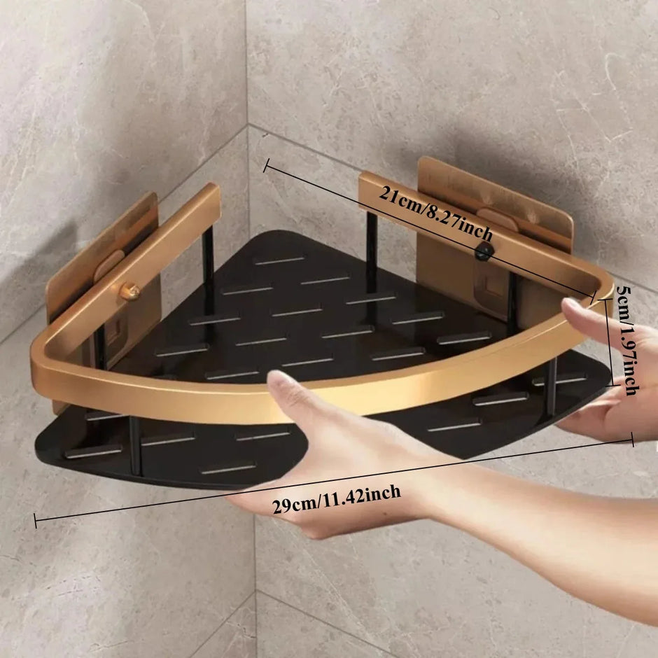 Corner shower shelf with gold frame and black tray held by a hand, showing dimensions against a tiled wall.