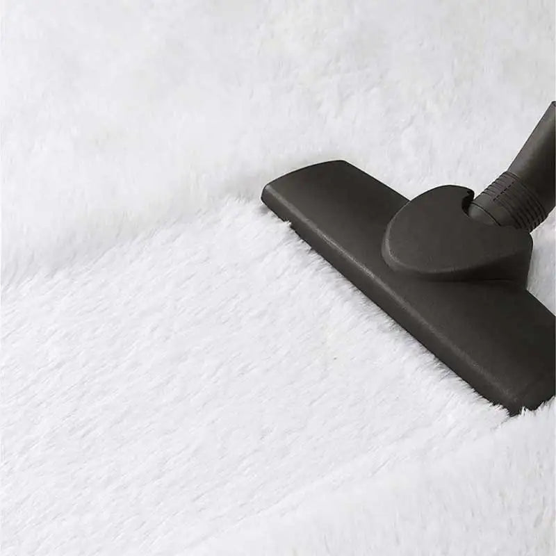 Black vacuum cleaner head cleaning a white textured surface