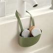 Green sponge holder with cleaning tools hanging on a kitchen sink.