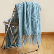 Light blue textured blanket draped over a metal chair on a wooden floor.