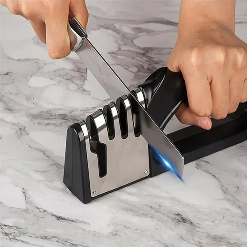 Person sharpening a knife using a black and silver knife sharpener on a marble surface.