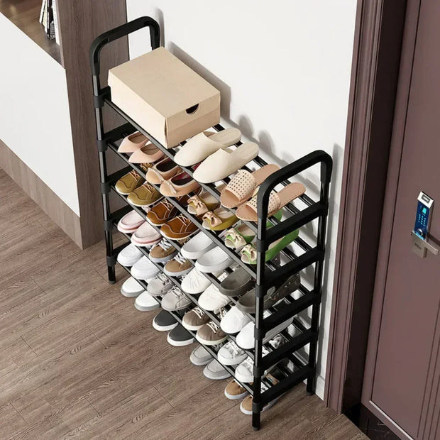 Black shoe rack with various shoes on a wooden floor next to a door.