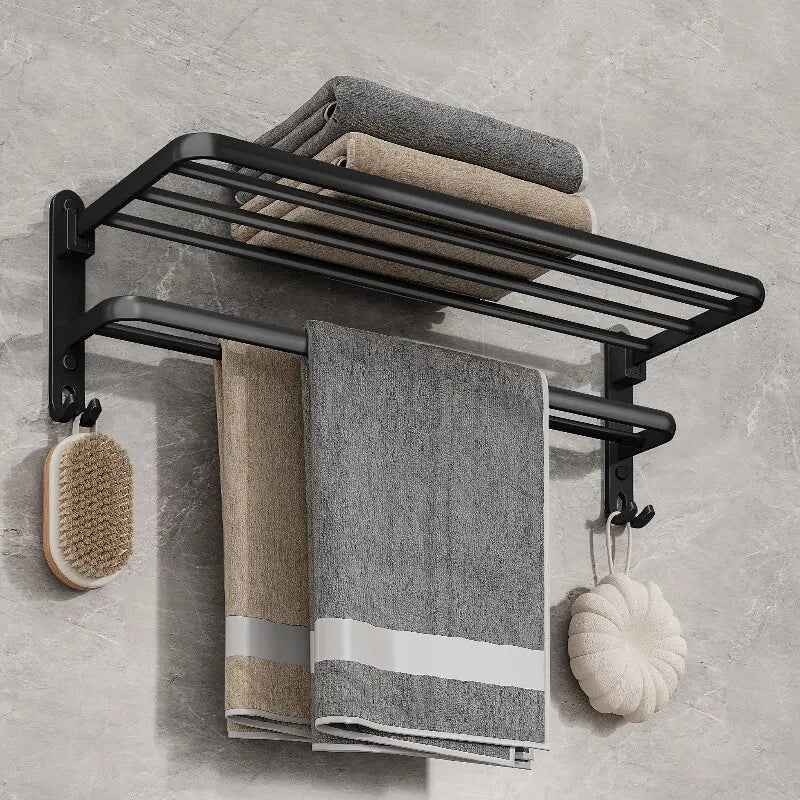 Black towel rack with folded towels and bath accessories on a gray wall.