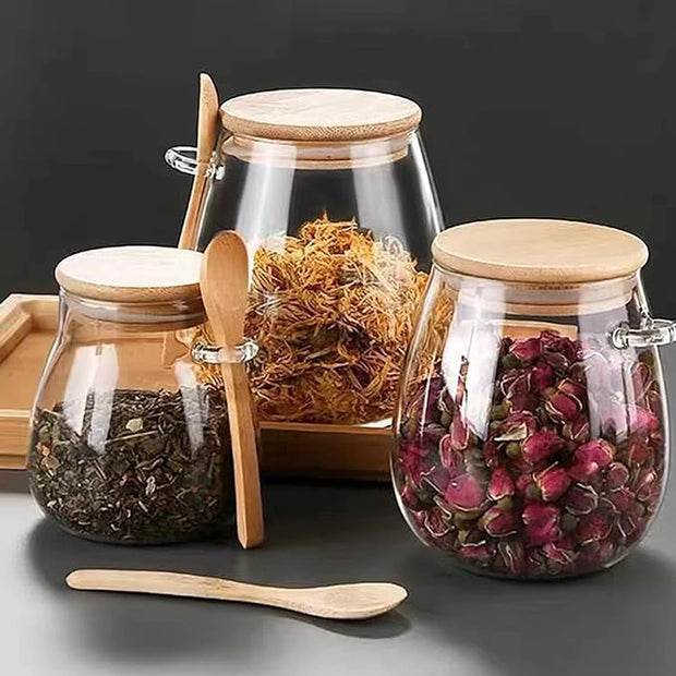 Three glass jars with wooden lids and spoons on a dark background