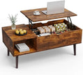 Wooden coffee table with lift-top design, displaying a laptop and other items on a white background.