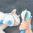 Person using a pet grooming brush on a white cat with a gray background