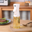 Spray bottle with oil on a kitchen counter with a plate of food in the background