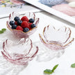 Three pink glass bowls with gold rims, one filled with berries, on a white surface.