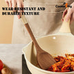 Person cooking with a wooden spoon in a ceramic pot, wearing an apron, on a neutral background.