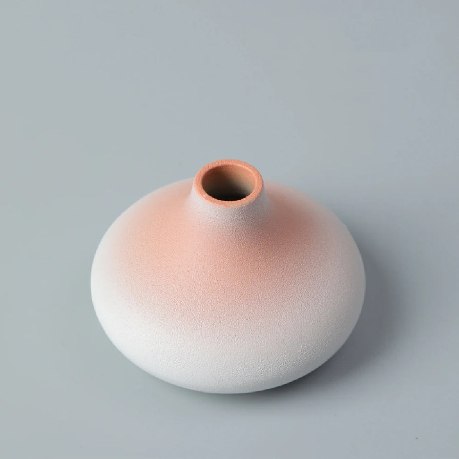 Ceramic vase with gradient color from pink to white on a gray background