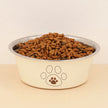 Dog food bowl with kibble and paw print design on a beige background