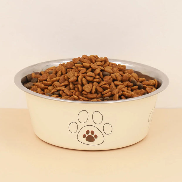 Dog food bowl with kibble and paw print design on a beige background