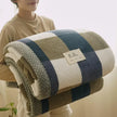 Person holding a striped blanket with a visible brand label.