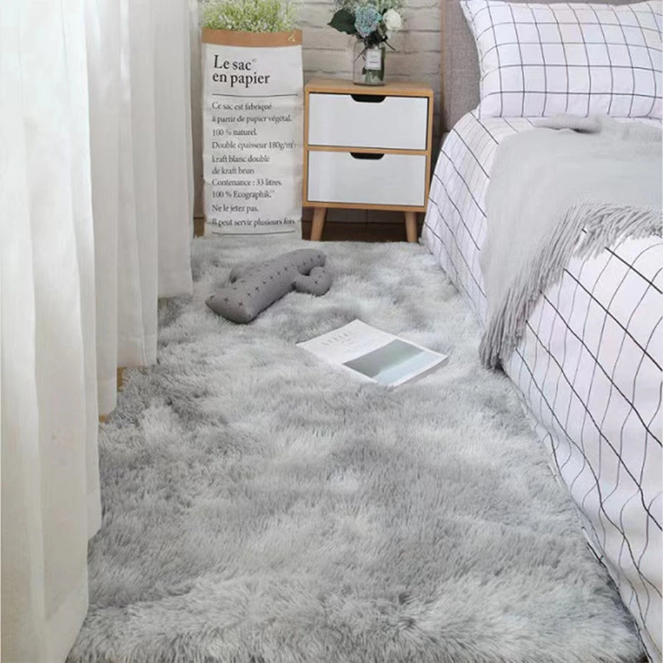 Gray fluffy rug in a bedroom with a bed, nightstand, and decorative items.