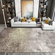 Modern living room with a gray and gold area rug, white sofa, and decorative pillows.