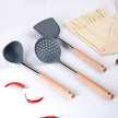 Set of gray kitchen utensils with wooden handles on a white surface with red peppers and a beige towel.