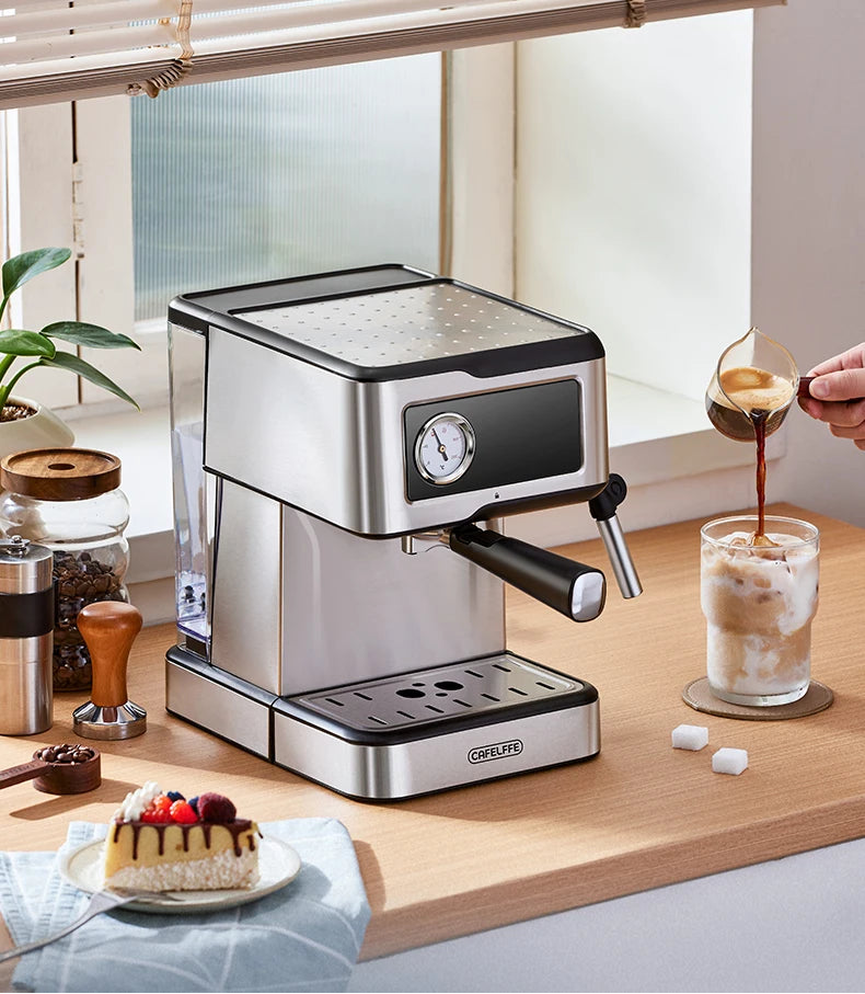Espresso machine on a kitchen counter with a glass of coffee and a small cake.