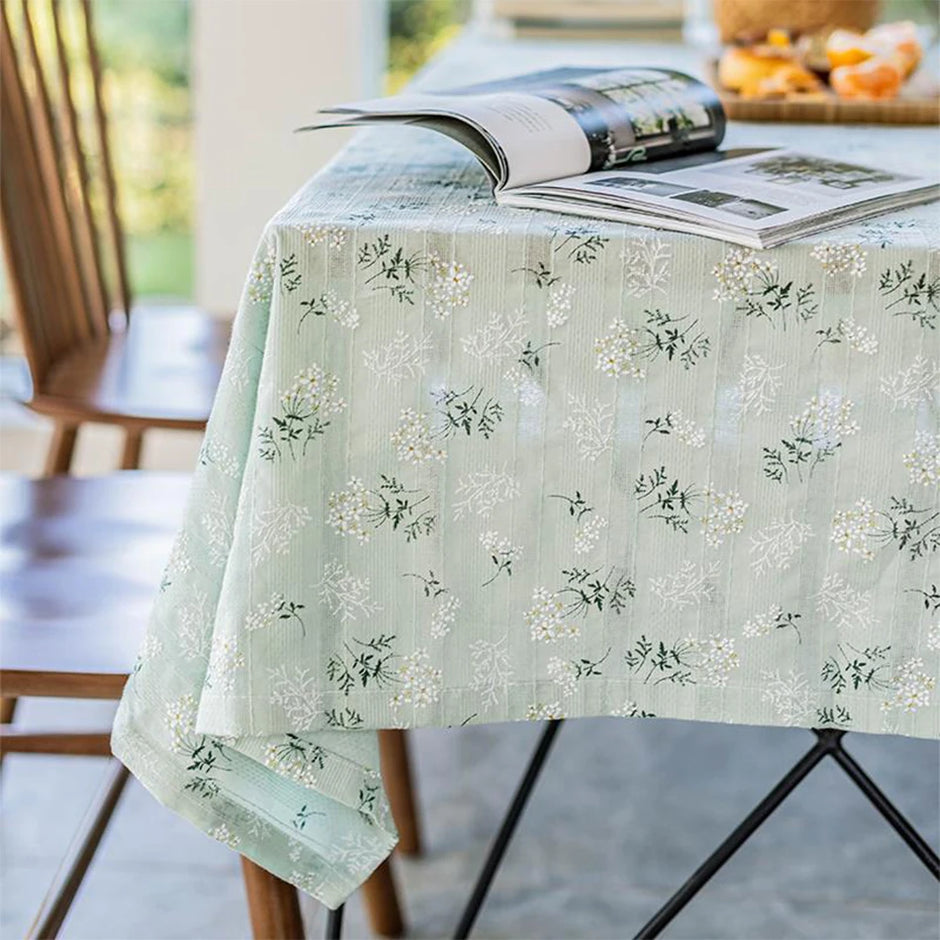 Floral patterned tablecloth on a table with a magazine underneath, outdoors.